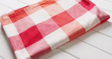 Close up of folded red and white checkered blanket on white background with copy space. Picnic day, food and nature concept.