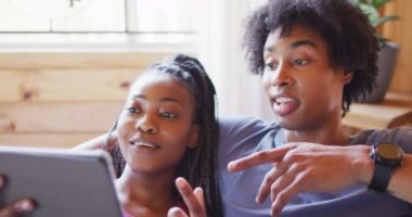 Mutlu Afro-Amerikan çift tablet kullanıyor, odunlukta kanepede oturuyor, ağır çekimde. Ev hayatı, kırsal alan ve doğa kavramı.