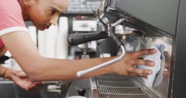 Kafede önlük giyip kahve makinesini temizleyen melez kadın barista. Yerel işletme sahibi ve konukseverlik kavramı.