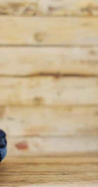 Vertical video of folded jeans with different shades on wooden background with copy space. Denim day, material, style and design concept.