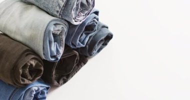 Close up of folded jeans with different shades on white background with copy space. Denim day, material, style and design concept.