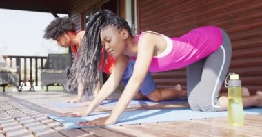 Mutlu Afro-Amerikan çifti yoga yapıyor ve kütük kulübesinde geriniyor, ağır çekimde. Yaşam tarzı, ev hayatı, kırsal ve doğa kavramı.