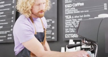 Kafkasyalı erkek barista kafeteryada bez ile kahve makinesini temizliyor. Yerel işletme sahibi ve konukseverlik kavramı.