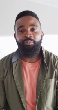 Vertical video portrait of happy african american man at home laughing to camera, in slow motion. Free time, happiness and lifestyle concept.