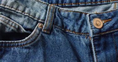 Close up of jeans on grey background with copy space. Denim day, material, style and design concept.