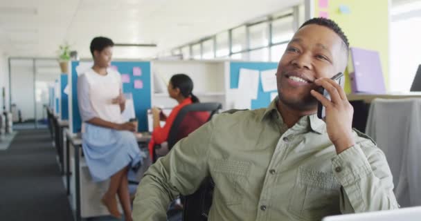 アフリカ系アメリカ人のビジネスマンがオフィスでスマートフォンで話してる オフィスで働くこと ビジネスコンセプト — ストック動画