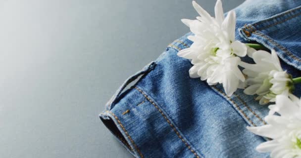 Close Van Jeans Met Witte Bloemen Grijze Achtergrond Met Kopieerruimte — Stockvideo