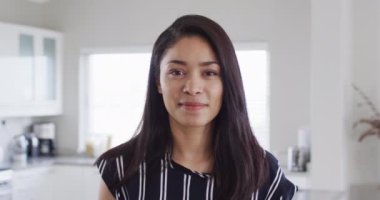 Portrait of happy biracial woman looking at camera and smiling, slow motion. Spending quality time at home, domestic life and lifestyle concept.