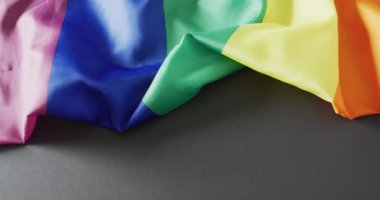 Video of rainbow wrinkly fabric over grey background with copy space. Gender, lgbt, queer, gay pride and equality concept.