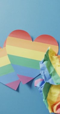 Vertical video of rainbow heart over blue background. Gender, lgbt, queer, gay pride and equality concept.