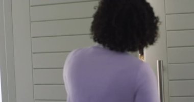 Happy diverse couple arriving at home of female friend with wine and pizzas, in slow motion. Free time, friendship and lifestyle concept.