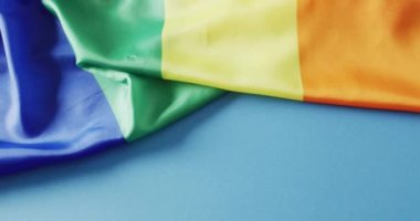 Video of rainbow fabric over blue background with copy space. Gender, lgbt, queer, gay pride and equality concept.