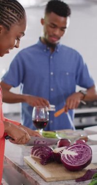 Vertical video of happy african american couple preparing meal together. Love, relationship, lifestyle and spending time together concept.