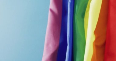 Video of rainbow fabric over blue background with copy space. Gender, lgbt, queer, gay pride and equality concept.