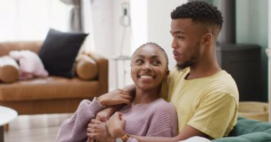 Happy african american couple talking and hugging on sofa. Lifestyle, relationship, spending free time together concept.