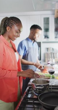 Vertical video of happy african american couple preparing meal. Lifestyle, relationship, spending free time together concept.