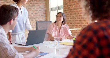 Diverse male and female colleagues in discussion in casual meeting, slow motion. Start up business, teamwork, inclusivity and communication concept.