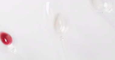 Glasses with wine leftovers lying on white surface with copy space. Wine, alcohol, beverage and wine tasting concept.