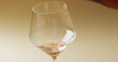 White wine pouring into glass over yellow background with copy space. Wine, alcohol, beverage and wine tasting concept.