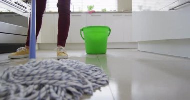 Caucasian woman cleaning floor with mop and bucket of water at home. Lifestyle and domestic life concept.