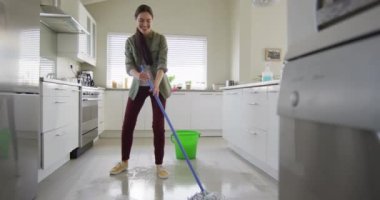 Happy caucasian woman cleaning floor with mop and bucket of water at home. Lifestyle and domestic life concept.