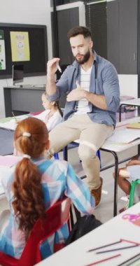 Kafkas erkek öğretmen ve kız öğrencilerin okulda öğrendiklerinin dikey videosu. Okul, eğitim ve öğrenim konsepti dijital olarak oluşturulmuş video.