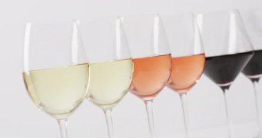 Row of diverse types of wines in glasses on white surface. Wine, alcohol, beverage and wine tasting concept.