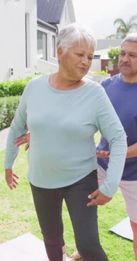 Bahçede yoga yapan mutlu çiftlerin dikey videosu. Evde kaliteli zaman geçirmek, emeklilik ve yaşam tarzı kavramı.