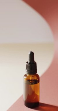 Vertical video of dropper serum bottle on pink background with copy space. Beauty products, cosmetics and skincare concept.