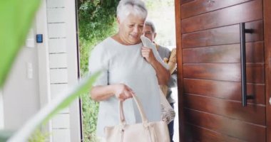 Happy senior diverse couple coming home with groceries. Spending quality time at home, retirement and lifestyle concept.