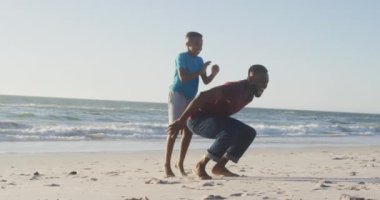 Video of happy african american father and son having fun on beach. Holidays, vacations, relations and spending quality family time together concept.