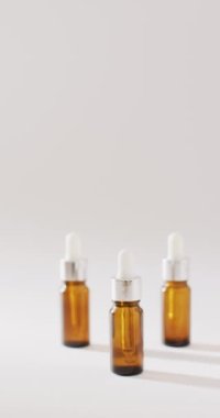 Vertical video of dropper serum bottles on white background with copy space. Beauty products, cosmetics and skincare concept.