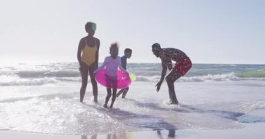 Video of happy african american family having fun o beach. Holidays, vacations, relax and spending quality family time together concept.