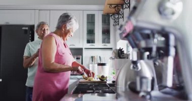 Happy senior biracial couple preparing healthy drink in kitchen. Spending quality time at home, retirement and lifestyle concept.