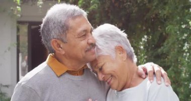 Happy senior diverse couple embracing in garden. Spending quality time at home, retirement and lifestyle concept.