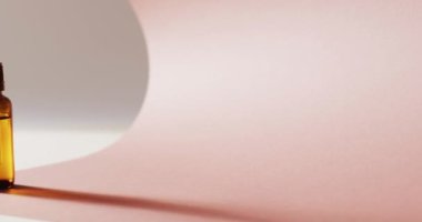 Close up of dropper serum bottle on pink background with copy space. Beauty products, cosmetics and skincare concept.