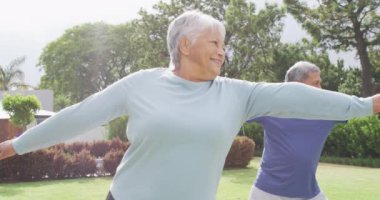 Happy senior diverse couple practicing yoga in garden. Spending quality time at home, retirement and lifestyle concept.