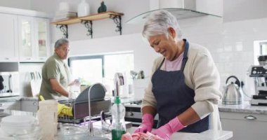 Happy senior biracial couple washing dishes in kitchen. Spending quality time at home, retirement and lifestyle concept.