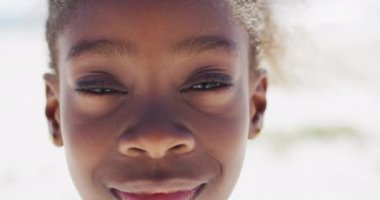 Happy african american girl smiling at camera on beach. Holidays, vacations, relax and spending quality family time together concept. 