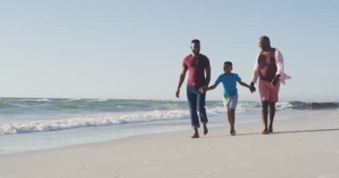 Video of african american happy african american grandfather, father and son walking on beach. Holidays, vacations, relations and spending quality family time together concept.