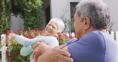 Happy senior diverse couple practicing yoga in garden. Spending quality time at home, retirement and lifestyle concept.