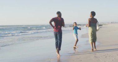 Video of happy african american family having fun on beach. Holidays, vacations, relations and spending quality family time together concept.