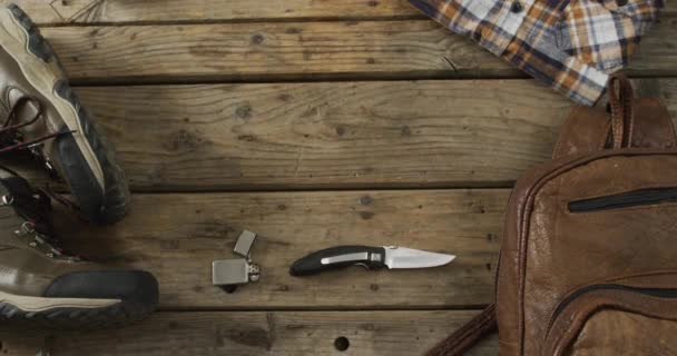 Campingausrüstung Mit Messer Feuerzeug Rucksack Stiefeln Und Kopierraum Auf Holzgrund — Stockvideo