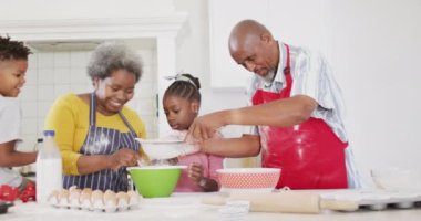 Gülümseyen Afrikalı Amerikalı büyükbabalar torunları ve torunlarıyla yavaş çekimde yemek pişiriyorlar. Aile, aşçılık ve birliktelik kavramı.