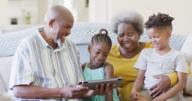 Afro-Amerikan dedeleri, torunu ve torunu tablet kullanıyor, ağır çekimde. Aile, birliktelik ve çocukluk kavramı.