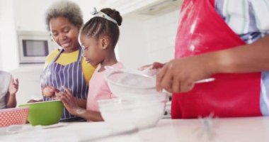Afro-Amerikan dedeleri torunları ve torunlarıyla yemek pişiriyor, yavaş çekimde. Aile, aşçılık ve birliktelik kavramı.