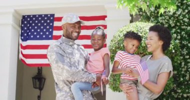 Mutlu Afro-Amerikan erkek asker ve karısı evlerinin önünde kızlarını ve oğullarını ağırdan alıyorlar. Aile, askerlik ve mezuniyet konsepti.