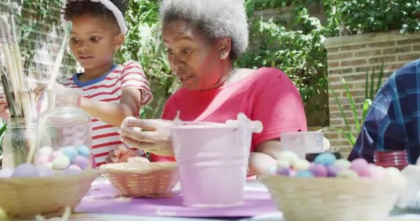 Χαρούμενη Αφροαμερικανή Γιαγιά Και Εγγονός Διακοσμούν Πασχαλινά Αυγά Ηλιόλουστο Κήπο — Αρχείο Βίντεο