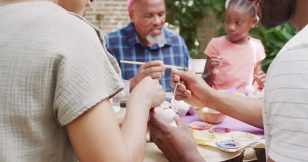 Glada Afrikanska Amerikanska Föräldrar Dotter Och Farfar Målar Påskägg Trädgården — Stockvideo