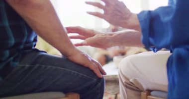 Caucasian man and woman holding hands in living room, with diverse senior friends, slow motion. Friendship, support and senior lifestyle.